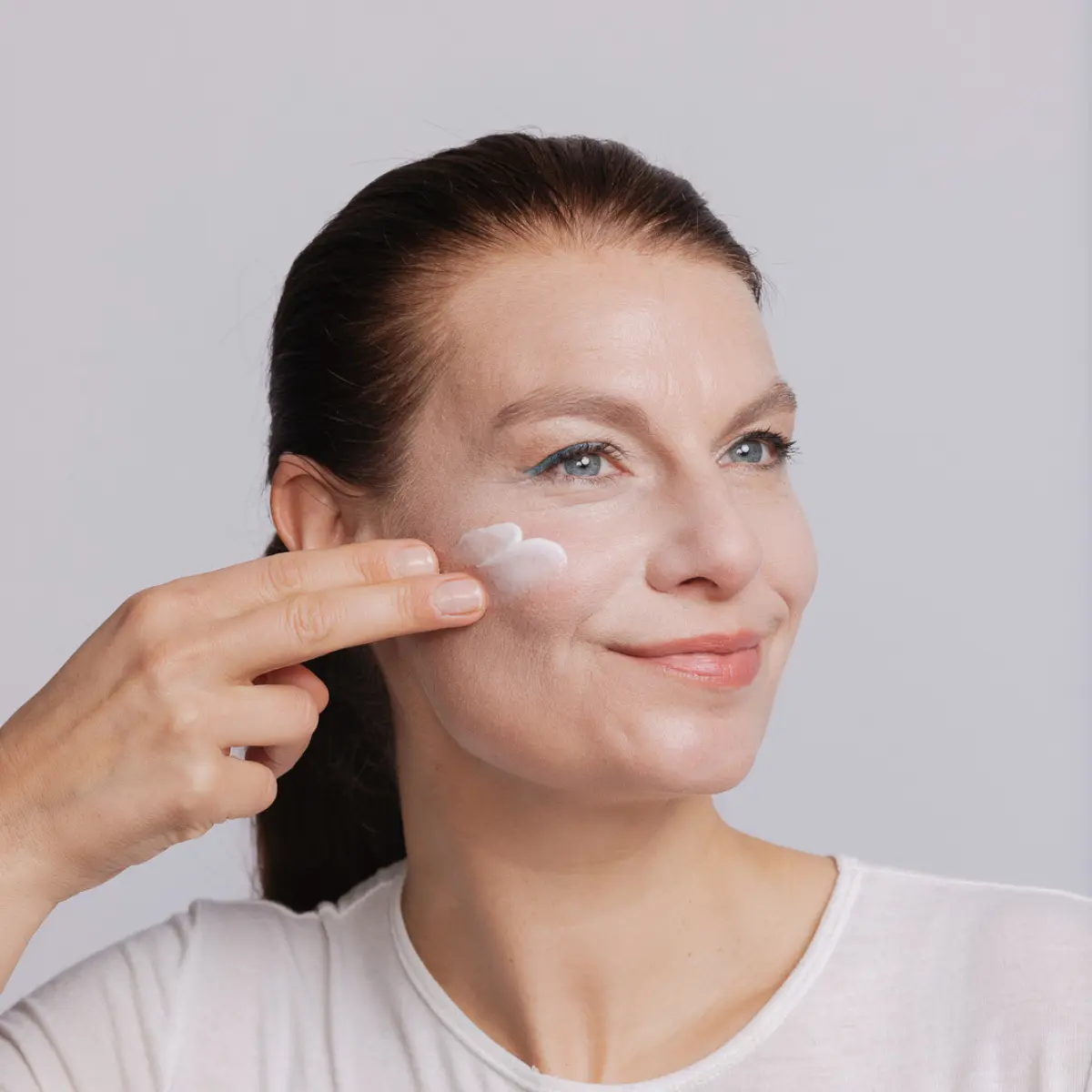 Frau trägt sanft Gesichtscreme von jolu auf ihr Gesicht auf