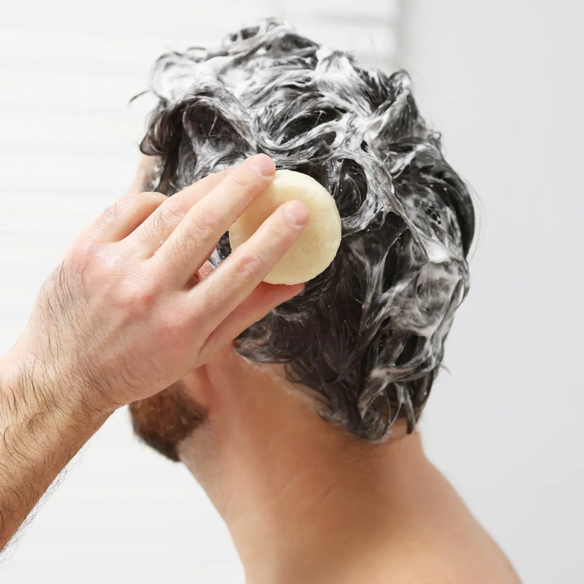 Mann wäscht Haare mit Jolu Shampoo Bar.
