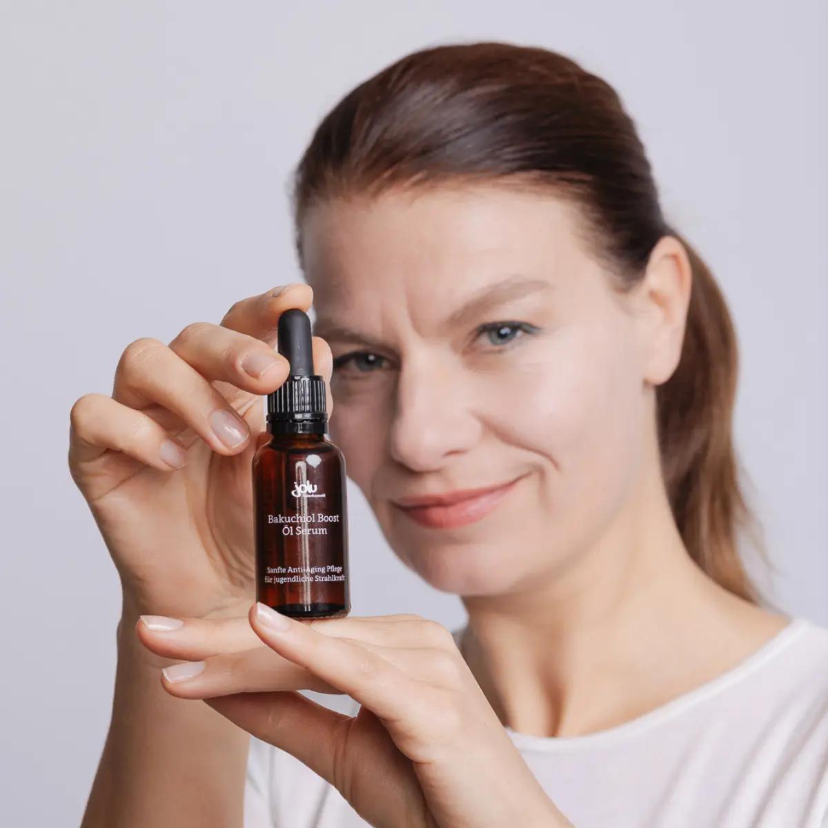 Frau präsentiert eine Flasche Bakuchiol-Serum